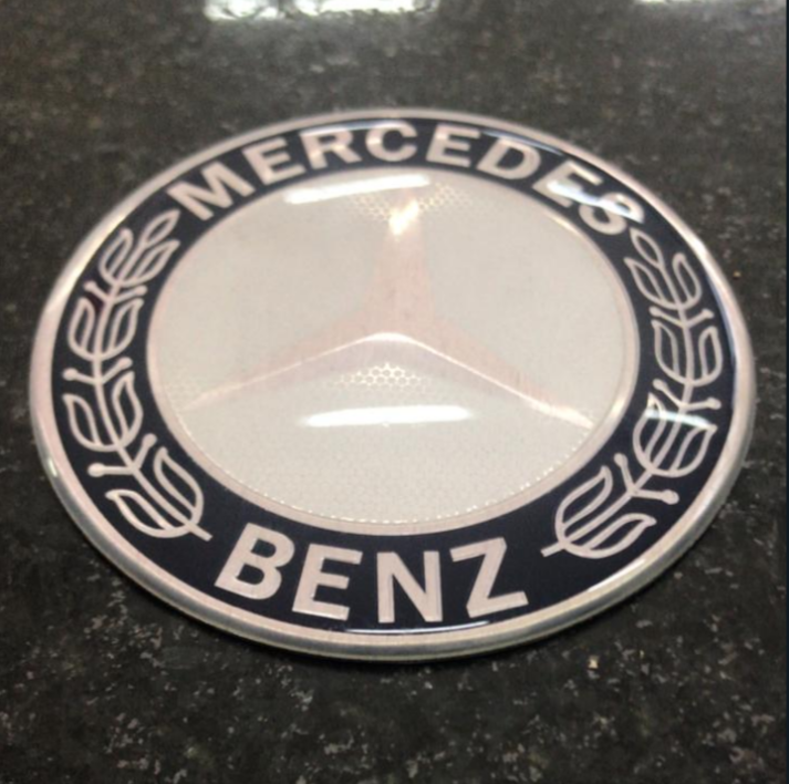 VL1289 - EMBLEMA CAPO CAFE MB ATEGO / MB AXOR / MB 1113 75MM ALUMINIO RESINADO